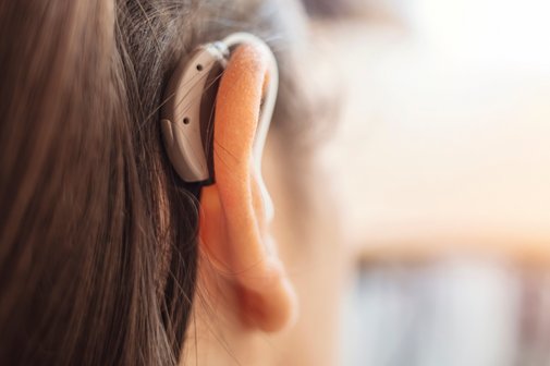 Kopf einer Frau mit einem H&ouml;rger&auml;t hinter dem rechten Ohr.