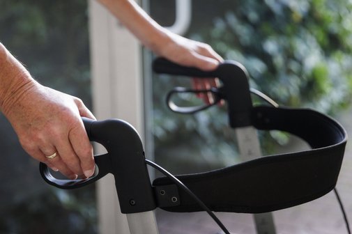 H&auml;nde eines &auml;lteren Mannes halten die Griffe eines Rollators.