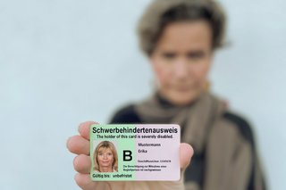 Eine Frau zeigt einen Schwerbehindertenausweis.