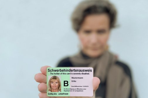 Eine Frau zeigt einen Schwerbehindertenausweis.